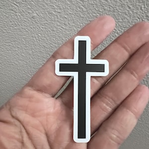 May include: A black cross sticker with a white outline.