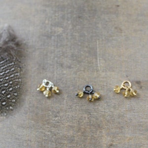 May include: Three charms in gold, silver and black with three small amber beads hanging from each.