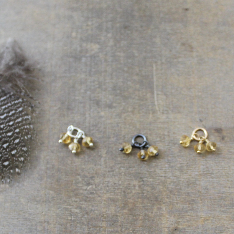 May include: Three charms in gold, silver and black with three small amber beads hanging from each.