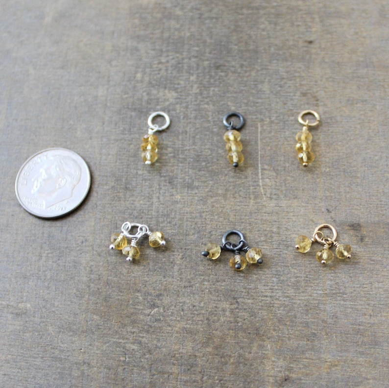 May include: Six different charms featuring small, round, golden citrine beads. Three charms have three beads, and three charms have a single bead.