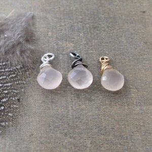 Peut inclure: Trois pendentifs en quartz rose rose avec des boucles en fil de fer dans des finitions argent, noir et or.
