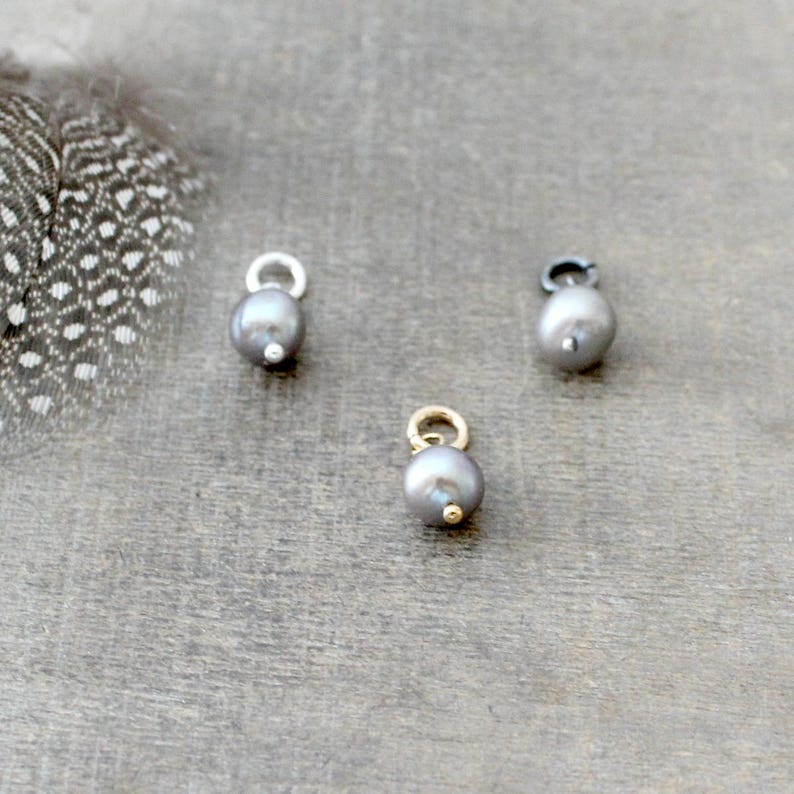May include: Three silver, gold, and black pearl charms with a loop for attaching to a necklace or bracelet.