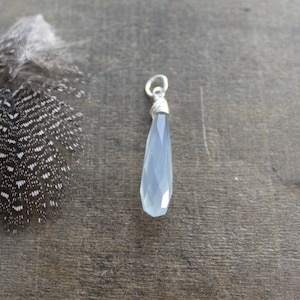 May include: A light blue gemstone pendant with a silver wire wrap. The pendant is teardrop shaped and has a faceted finish.