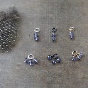May include: Five charms with amethyst beads in silver, gold, and black finishes. The charms are in the shape of a cluster of beads.