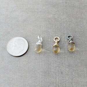 May include: Three gold-toned teardrop-shaped charms with a wire-wrapped design. The charms are approximately the size of a dime.