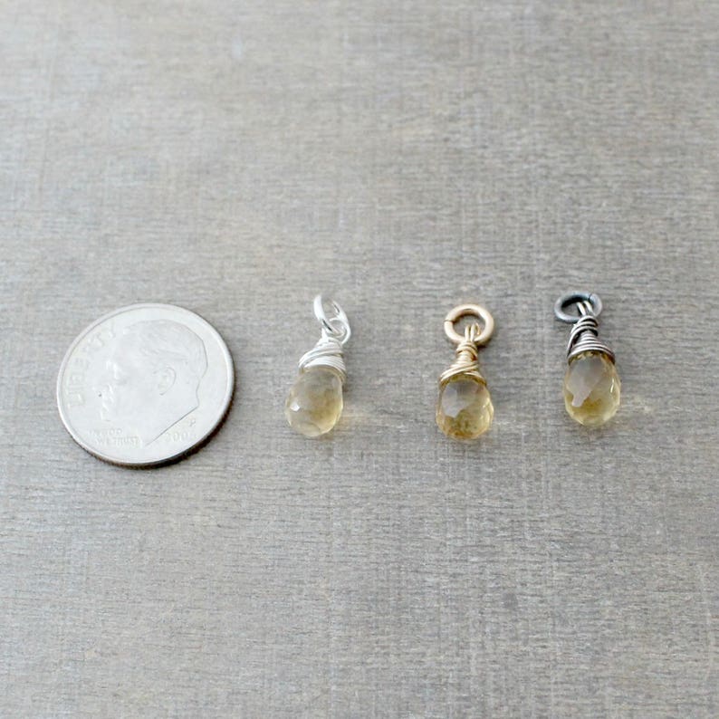 May include: Three gold-toned teardrop-shaped charms with a wire-wrapped design. The charms are approximately the size of a dime.