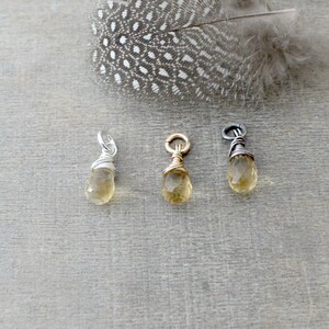 May include: Three wire-wrapped teardrop-shaped pendants with a light yellow gemstone. The pendants are made with silver, gold, and black wire.