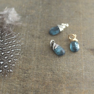 May include: Three wire-wrapped pendants with blue gemstone drops. The pendants are made with silver and gold wire.