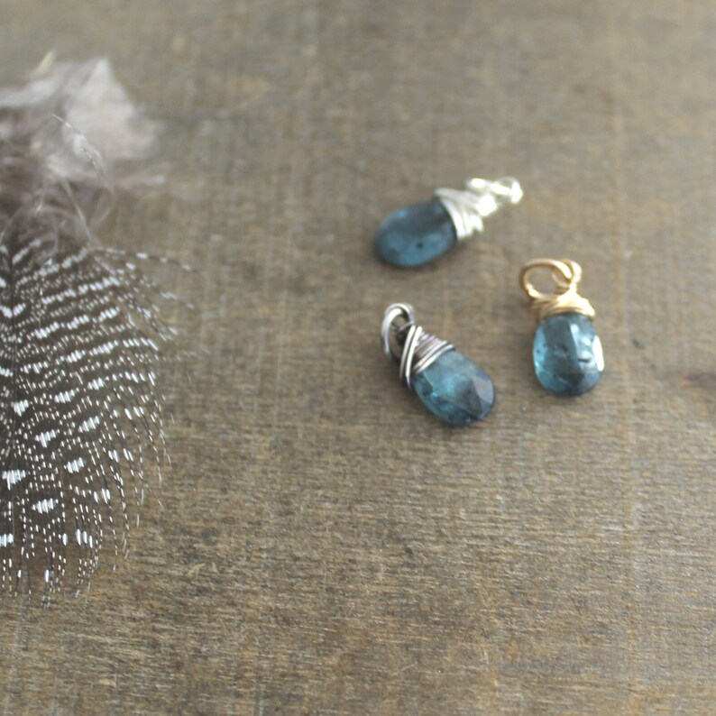 May include: Three wire-wrapped pendants with blue gemstone drops. The pendants are made with silver and gold wire.