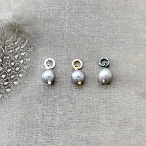 May include: Three silver, gold, and black charms with a dark gray pearl pendant.