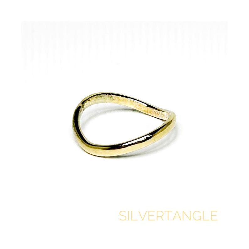 wavy gold ring against a white background