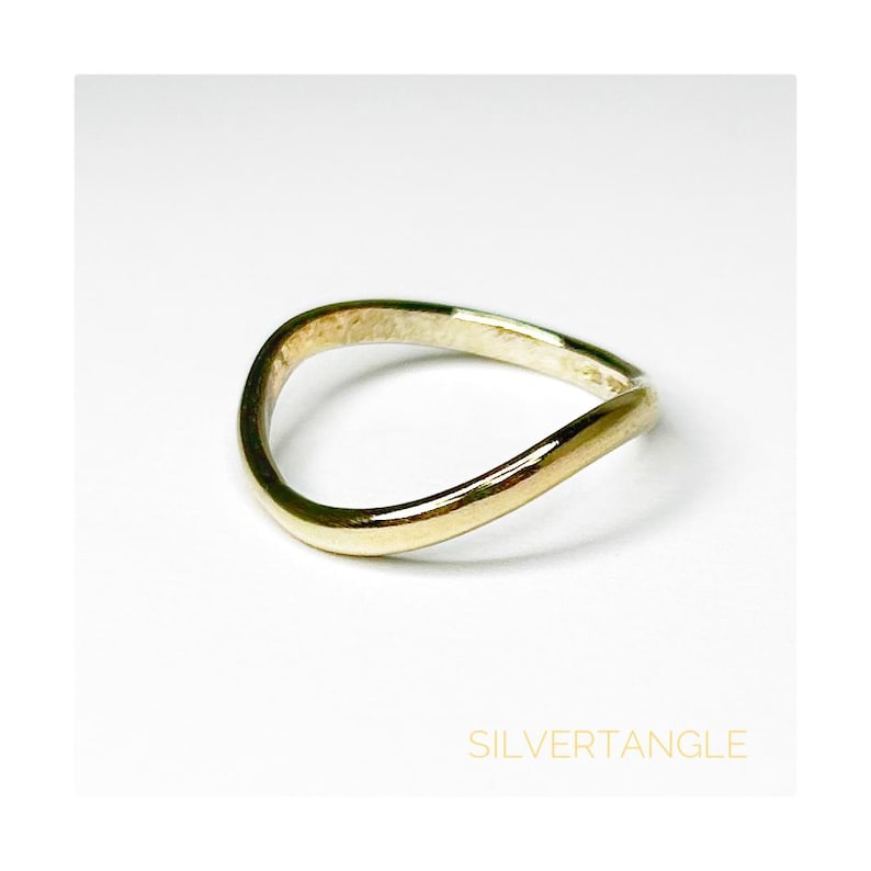 wavy gold ring against a white background