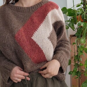 May include: A brown, cream and rust coloured knitted jumper with a diagonal stripe pattern.