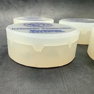 Op de afbeelding: Vier doorzichtige plastic containers met een wit, ondoorzichtig deksel. De deksels hebben een blauw logo met de tekst "ICESHADOW PRODUCTIONS" en daaronder de tekst "Blackbrier 1234567890".