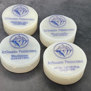 May include: Four white round containers with blue mountain range logos and text. The text on the containers reads "IceShadow Productions" with different sub-titles: "Industrial Bold", "Flourish and Flow", "Blackletter", and "Metal Cathedral". Each container has a phone number: 1234567890.