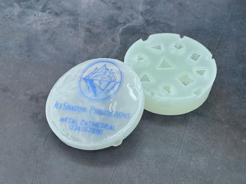 Op de afbeelding: Twee doorschijnende ronde witte mallen. E&eacute;n mal heeft een logo met de tekst "Ice Shadow Productions" en "Metal Cathedral 1774 567 890". De andere mal heeft een patroon van driehoeken en vierkanten.