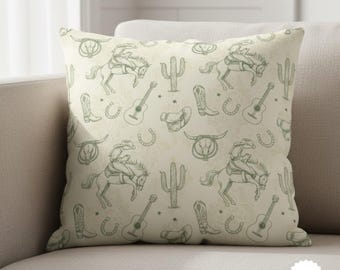 May include: Square throw pillow with a repeating pattern of cowboy-themed illustrations in green on a cream background. The design includes cowboys on horses, guitars, boots, cacti, and horseshoes.