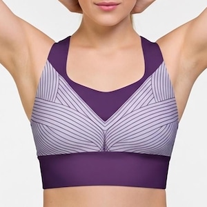 May include: A purple sports bra with a geometric design. The bra features a wide band and straps in a darker shade of purple, with a light purple and white striped pattern on the cups.