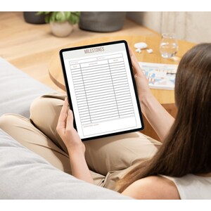 May include: A digital tablet displaying a blank "MILESTONES" checklist with columns for "Date", "Milestone", and "Notes".