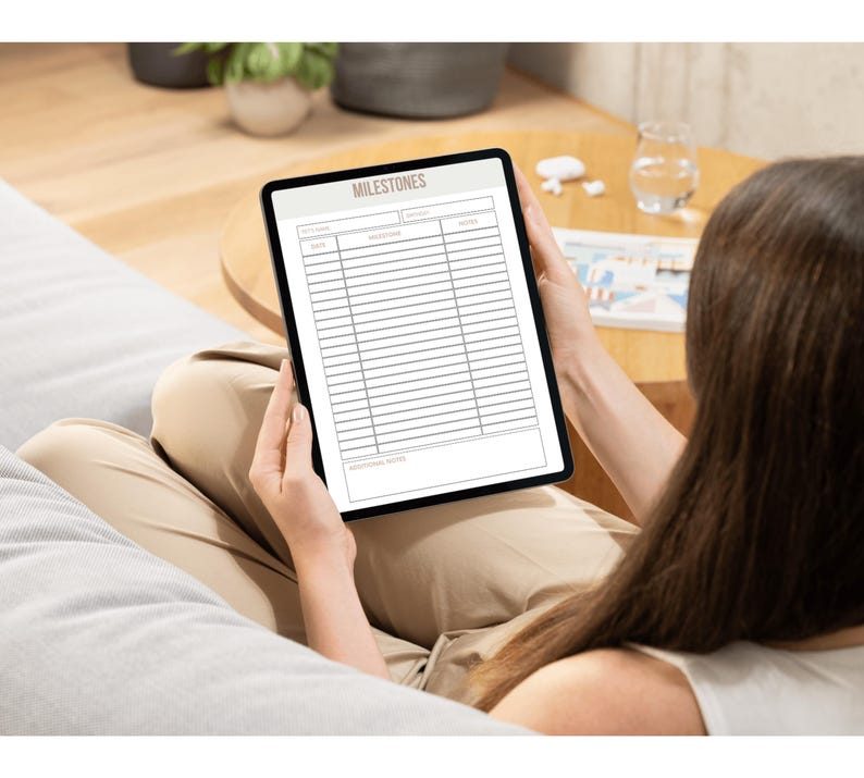 May include: A digital tablet displaying a blank "MILESTONES" checklist with columns for "Date", "Milestone", and "Notes".