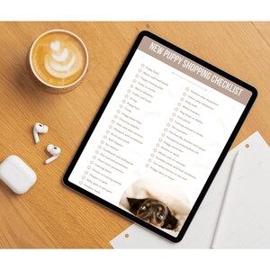 May include: A checklist on a tablet with the title "New Puppy Shopping Checklist". The checklist includes items such as puppy food, training pads, bed and blankets, collar and leash, toys, puppy play equipment, and more. A cute puppy is peeking out from under a blanket in the bottom right corner of the image.