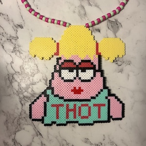 May include: A handmade beaded necklace featuring a pixelated Patrick Star pendant with the word "THOT" in red letters on a teal shirt. The necklace has a pink and green beaded chain and a yellow hairpiece.
