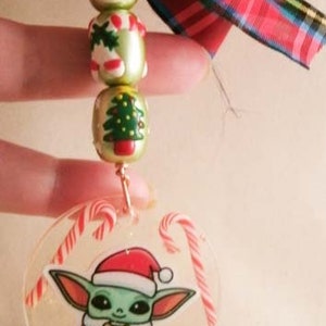 Peut inclure: Une d&eacute;coration de No&euml;l repr&eacute;sentant un personnage vert et blanc portant un bonnet de P&egrave;re No&euml;l rouge. L'ornement est transparent et contient des cannes en sucre rouge et blanc. L'ornement est attach&eacute; &agrave; une cha&icirc;ne dor&eacute;e et &agrave; un ruban &eacute;cossais rouge et vert.