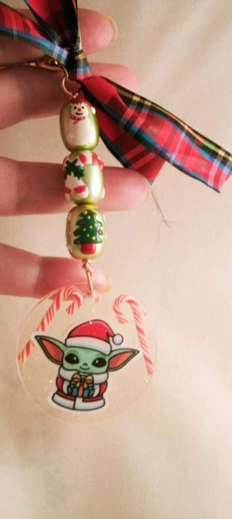 Peut inclure: Une d&eacute;coration de No&euml;l repr&eacute;sentant un personnage vert et blanc portant un bonnet de P&egrave;re No&euml;l rouge. L'ornement est transparent et contient des cannes en sucre rouge et blanc. L'ornement est attach&eacute; &agrave; une cha&icirc;ne dor&eacute;e et &agrave; un ruban &eacute;cossais rouge et vert.