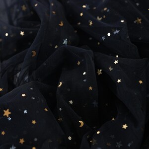 May include: Black tulle fabric with gold and silver star and crescent moon embellishments. The fabric is gathered and draped, creating a textured effect. The brand name "lalathread" is visible in the upper right corner.
