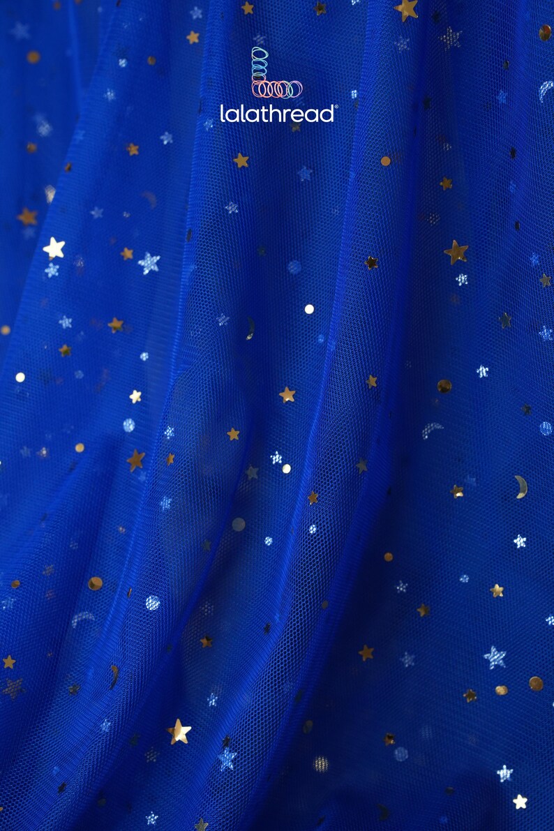 May include: Royal blue tulle fabric with gold star and dot sequins. The fabric has a delicate, sheer appearance, with the text "lalathread" in the upper right corner. Ideal for crafting projects, costumes, or decorative purposes.