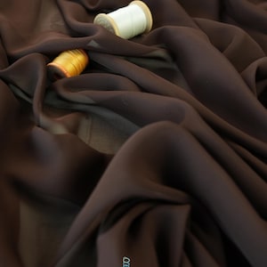 May include: Dark brown fabric with soft folds, and two spools of thread. One spool is white, and the other is gold. The fabric has a slight sheen. The logo "lalathread" is in the bottom right corner.