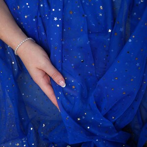 May include: Royal blue fabric with gold and silver star and crescent moon embellishments. The fabric is draped, with a hand holding the material. A pearl bracelet is visible. The logo "lalathread" is in the bottom right corner.