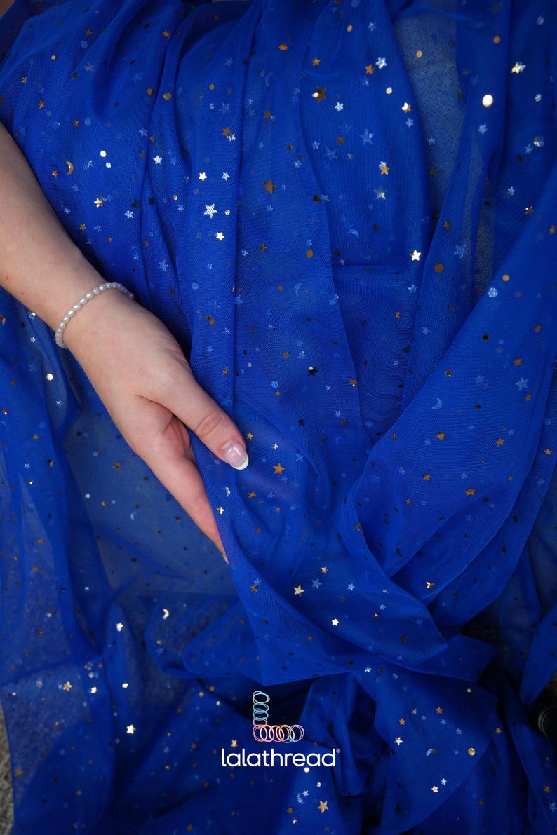 May include: Royal blue fabric with gold and silver star and crescent moon embellishments. The fabric is draped, with a hand holding the material. A pearl bracelet is visible. The logo "lalathread" is in the bottom right corner.