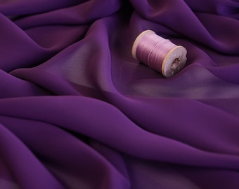 May include: A close-up of flowing, deep purple fabric with soft folds. A wooden spool of pink thread rests on the fabric. The fabric is likely chiffon or a similar lightweight material. The logo "lalathread" is in the bottom right corner.