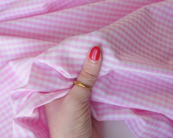 May include: Pink and white gingham fabric with the text "lalathread" in the upper left corner. The fabric is being held by a hand wearing a gold ring and a bracelet. The fabric is folded and has a soft texture.