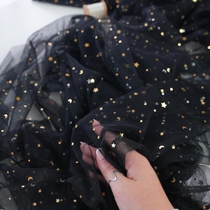 May include: Black tulle fabric with gold stars and crescent moons. The fabric is semi-sheer and has a delicate texture. The brand name "lalathread" is visible in the upper right corner.