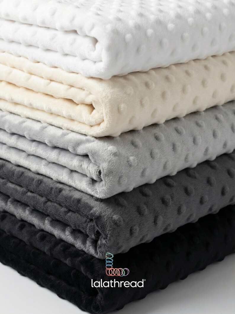 May include: Five folded blankets in a stack, ranging in colour from white to black. Each blanket has a textured, dotted pattern. The brand name "lalathread" is visible at the bottom.