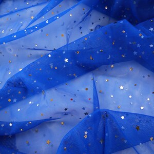 May include: Royal blue tulle fabric scattered with gold stars, moons, and small dots. The fabric is semi-sheer and has a delicate, flowing appearance. The brand name "lalathread" is visible in the upper right corner. This fabric is suitable for crafting and apparel.