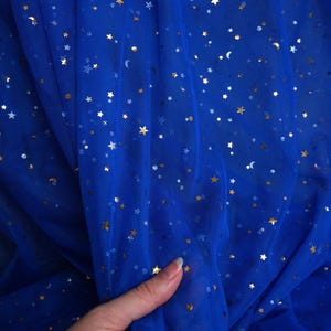 May include: Royal blue tulle fabric with gold and silver star and moon accents. The fabric is semi-sheer and has a delicate, flowing drape. The brand name "lalathread" is visible in the upper right corner. Ideal for crafting and special occasion apparel.