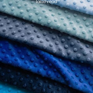 May include: Close-up of several layers of blue fabric with a textured, dotted pattern. The fabric colors range from light blue to deep navy, creating a gradient effect. The brand name "lalathread" is visible in the top right corner.
