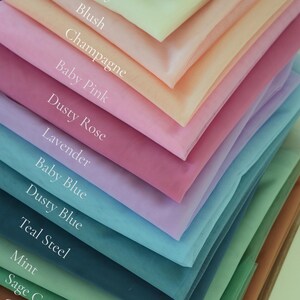 May include: A layered display of tulle fabric swatches in various colors. The colors include white, ivory, blush, champagne, baby pink, dusty rose, lavender, baby blue, dusty blue, teal steel, mint, sage green, caramel, and brown.