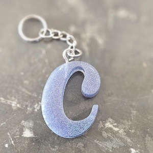 May include: A silver keychain with a sparkly light blue letter C charm.