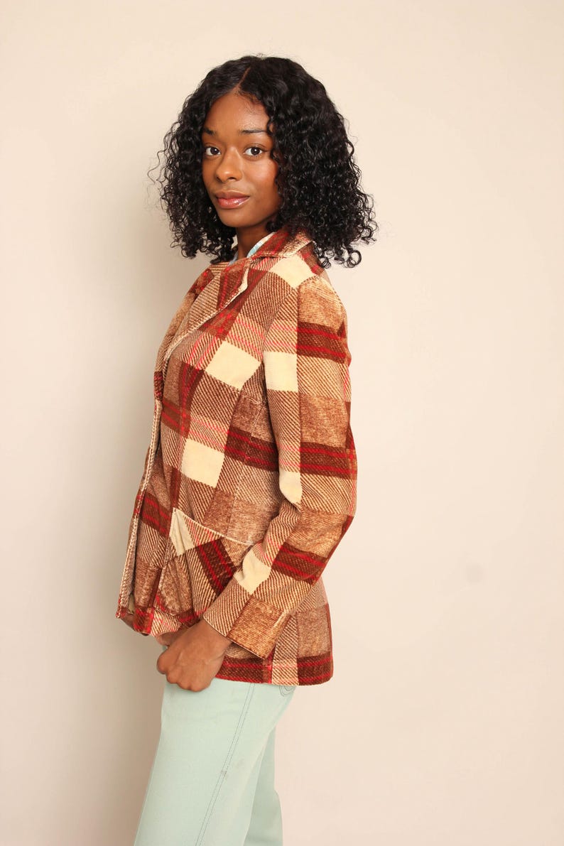 以下が含まれることがあります： 茶色、赤、クリーム色のチェック柄ブレザー。ノッチドラペルと2つのフロントポケットが付いています。 ブレザーはヴィンテージスタイルで、テーラードフィットです。 モデルはライトブルーのジーンズを着用しています。