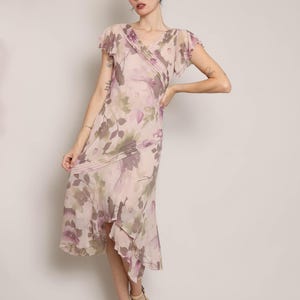 K&ouml;nnte beinhalten: Ein rosafarbenes Midi-Kleid mit floralem Druck, V-Ausschnitt und kurzen &Auml;rmeln. Das Kleid hat einen R&uuml;schen-Saum und eine High-Low-Silhouette.