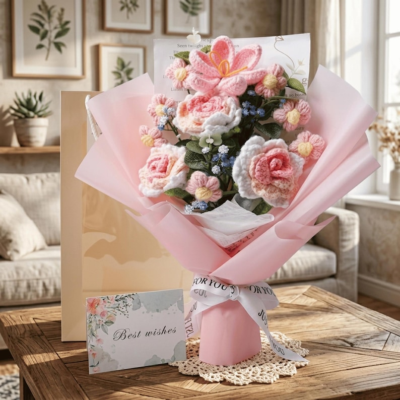 May include: A bouquet of handmade crochet flowers in shades of pink, white, and yellow, wrapped in pink paper. The bouquet is tied with a white ribbon that says "For You". A card with the words "Best wishes" is included.