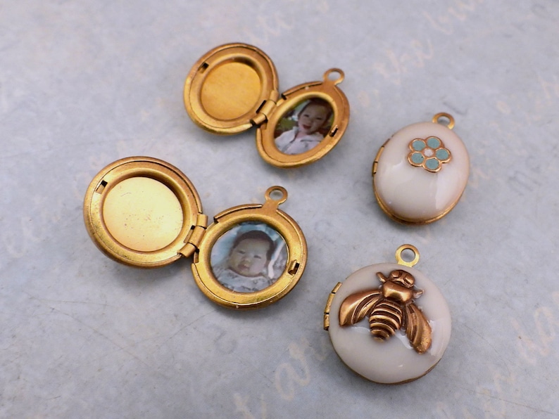 May include: Four gold-toned locket pendants with different designs. One locket has a photo of a baby, another has a photo of a child, one has a blue flower design, and the last one has a bee design.
