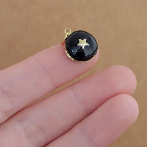 May include: A small gold locket with a black enamel finish and a gold star design.