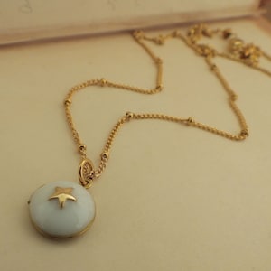 May include: A gold chain necklace with a white enamel pendant featuring a gold star.
