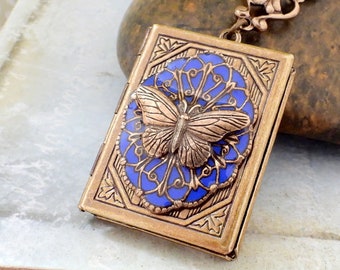 May include: A gold-toned locket with a blue enamel design and a butterfly charm. The locket has a detailed, ornate design.