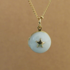 May include: A gold chain necklace with a white locket pendant featuring a gold star design.